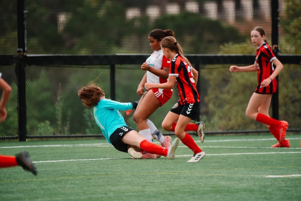 Goalkeeper diving low to make a save during a youth match